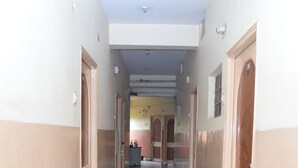 Un long couloir étroit, doté d’un sol en marbre et de murs de couleur beige.