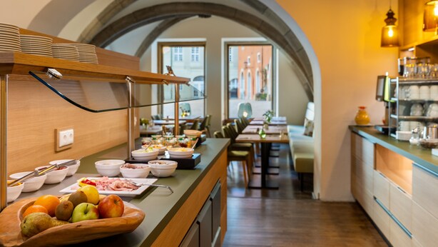 Un buffet de petit-déjeuner proposant une variété d'aliments et un saladier en bois rempli de fruits.