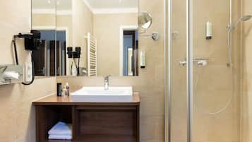 Ein modernes Badezimmer mit einer gläsernen Dusche, einem Waschbecken mit Spiegel und einem Handtuchhalter.