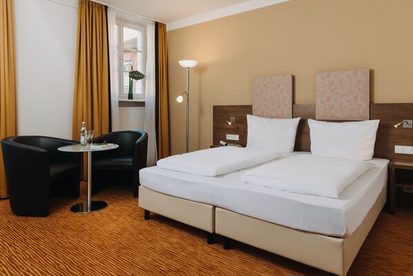 A hotel room with a bed, two bedside tables, a desk with a chair, and a window with curtains. - Altstadthotel Arch (Regensburg)