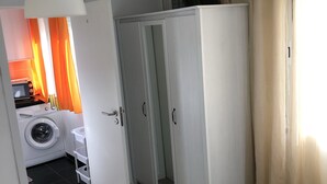 A compact room with a washing machine, a small table, and a cabinet with a mirror. - Duplex proximo do aeroporto lisboa (Lisboa)