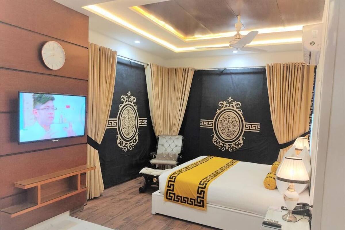 A modern bedroom with a bed, a TV, a chair, and curtains.