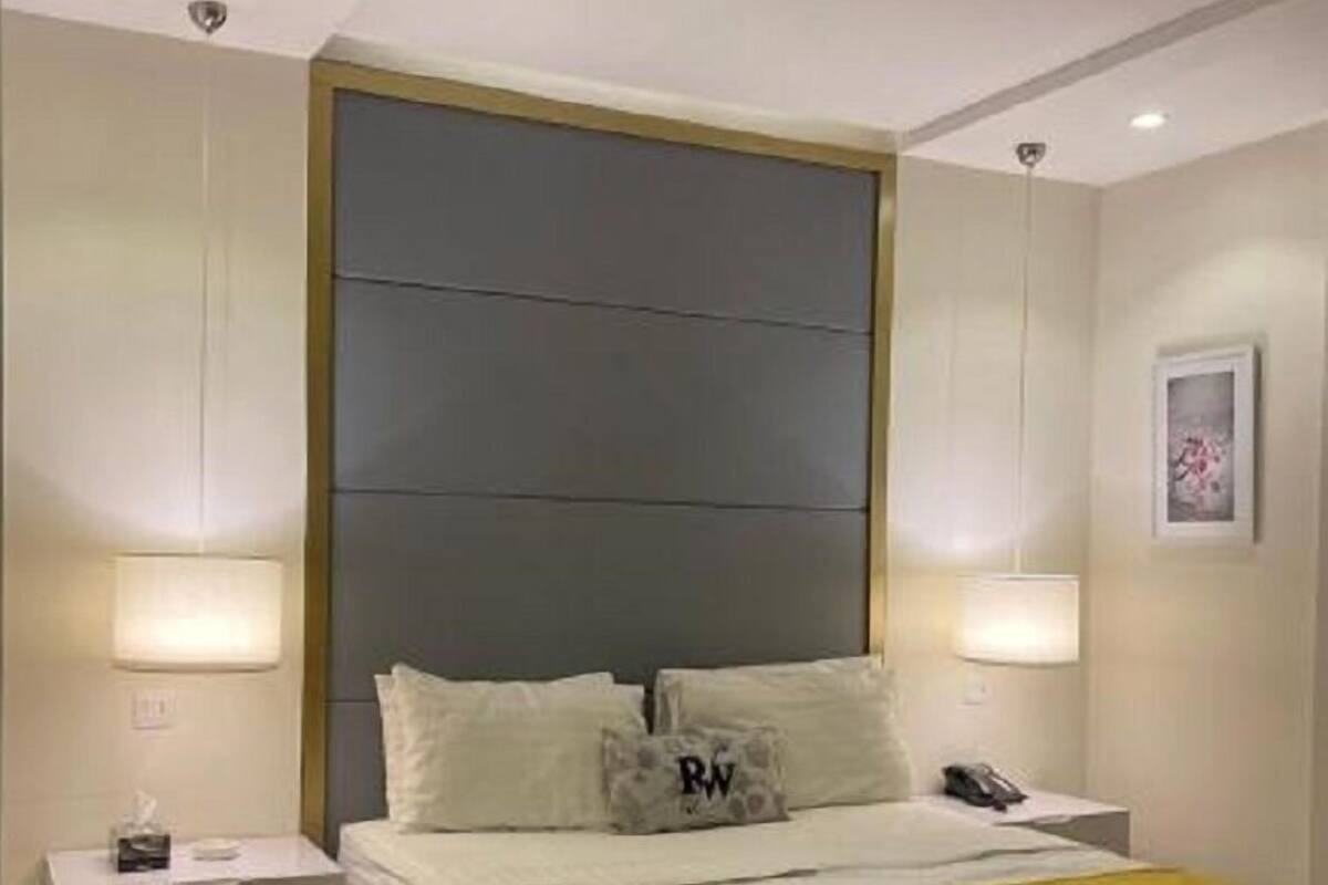 A modern bedroom with a large bed, bedside tables, and a headboard.
