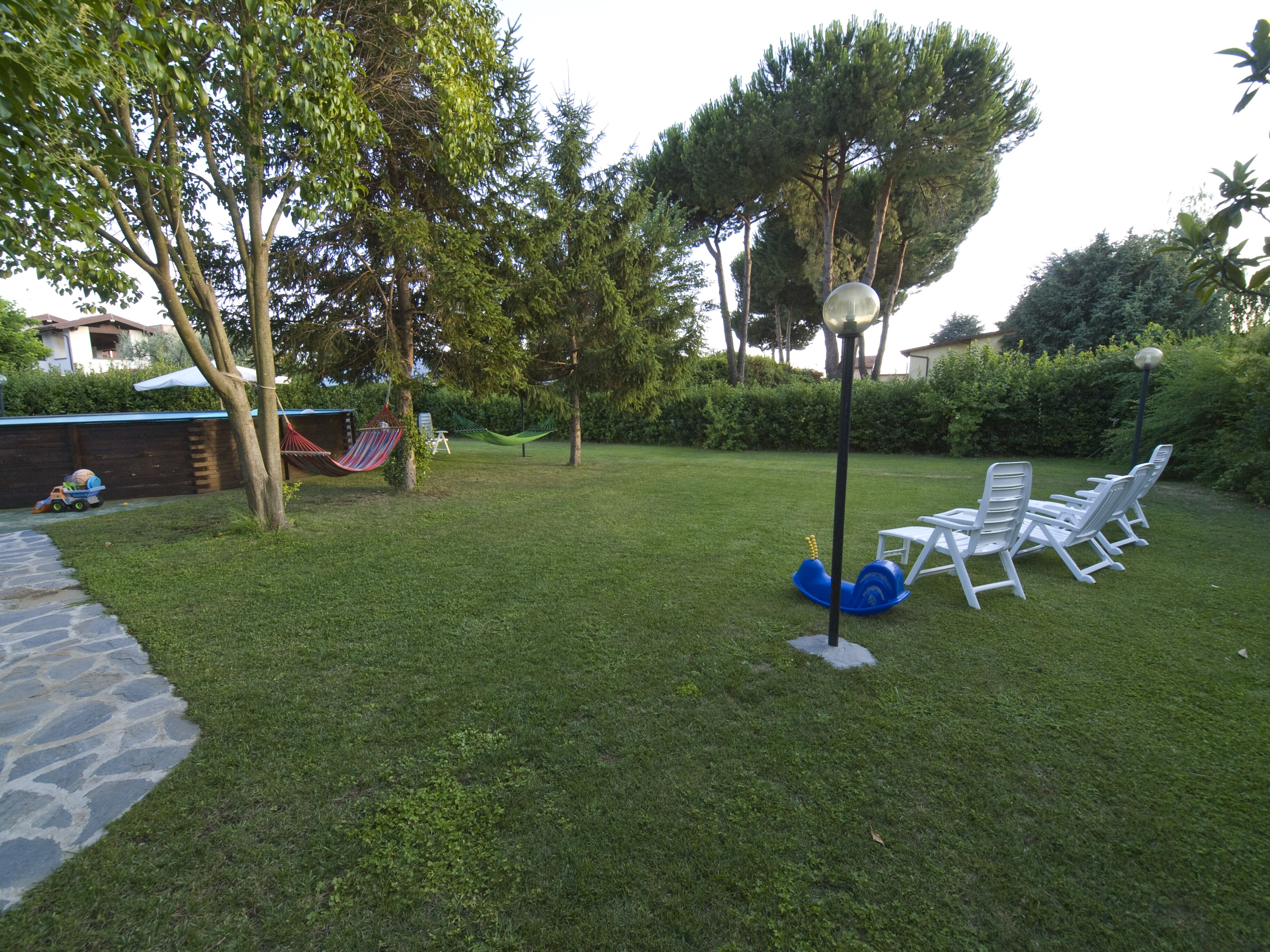 A grassy backyard with a hammock, a play area, and outdoor furniture.