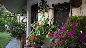 A stone building with a covered porch, potted plants, and a wooden bench. - Moon Nest - Apartment in villa, 10 min from the sea private garden pool (Massarosa)