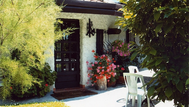 A building with a tiled roof, a black door, and a white chair outside. - Moon Nest - Apartment in villa, 10 min from the sea private garden pool (Massarosa)