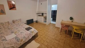 A bedroom with a bed, a desk, and a chair. There is a window and a door leading to another room. - Independent, private studio (Persan)