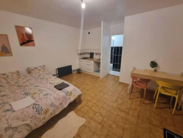 A bedroom with a bed, a desk, and a chair. There is a window and a door leading to another room.