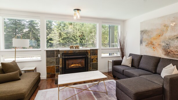 A modern living room with a fireplace, large windows, and a contemporary art piece.