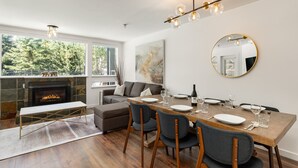 A modern dining area with a fireplace, a round mirror, and a view of the outdoors.