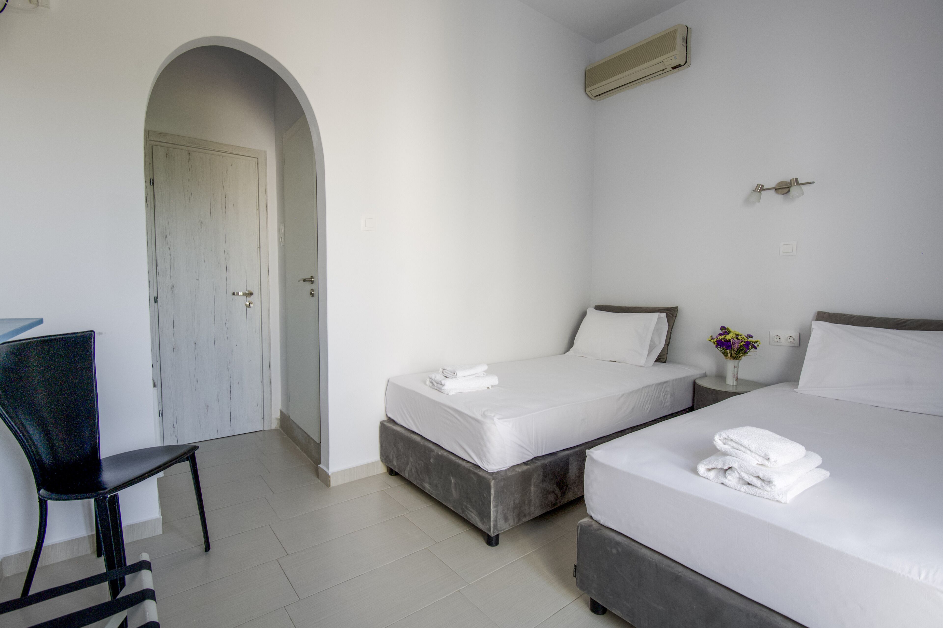 A hotel room with two beds, a desk, and a chair.
