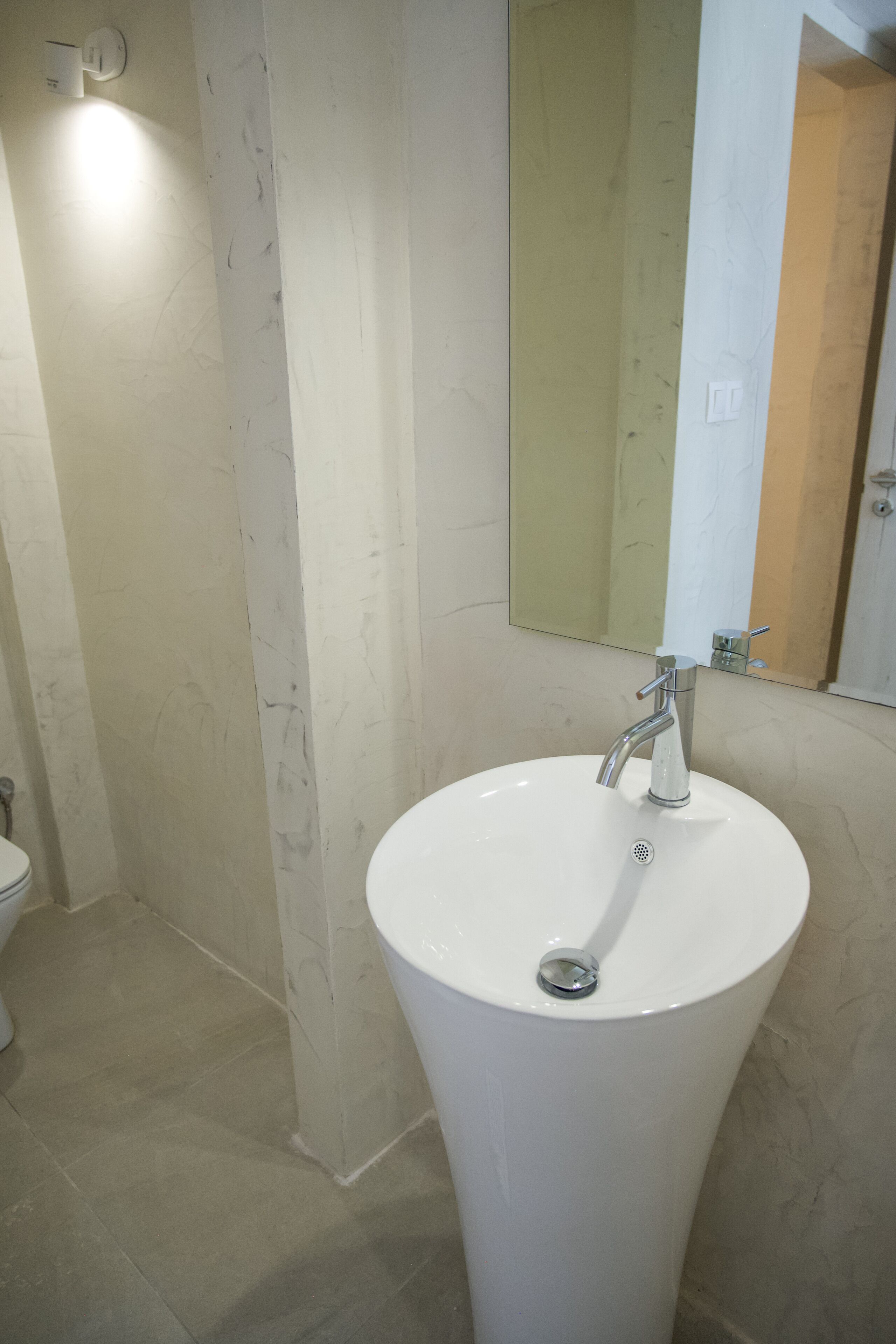 A bathroom with a white sink, a mirror, and a toilet.