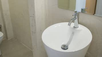 A bathroom with a white sink, a mirror, and a toilet.