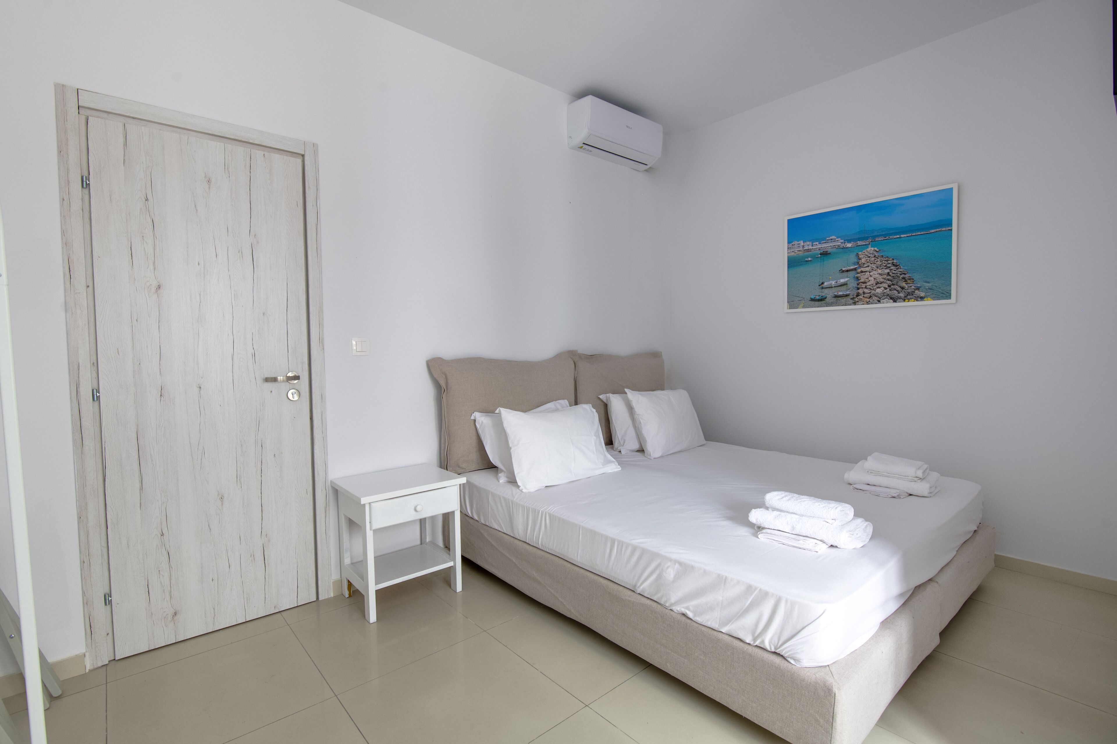 Une chambre à coucher avec un lit, une table de chevet, une porte et un tableau au mur.
