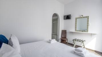 Habitación de hotel con cama, un taburete de madera, un espejo y un armario.