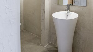 A bathroom with a large white sink, a mirror, and a shower area. - Porto Bello Hotel (Paros)