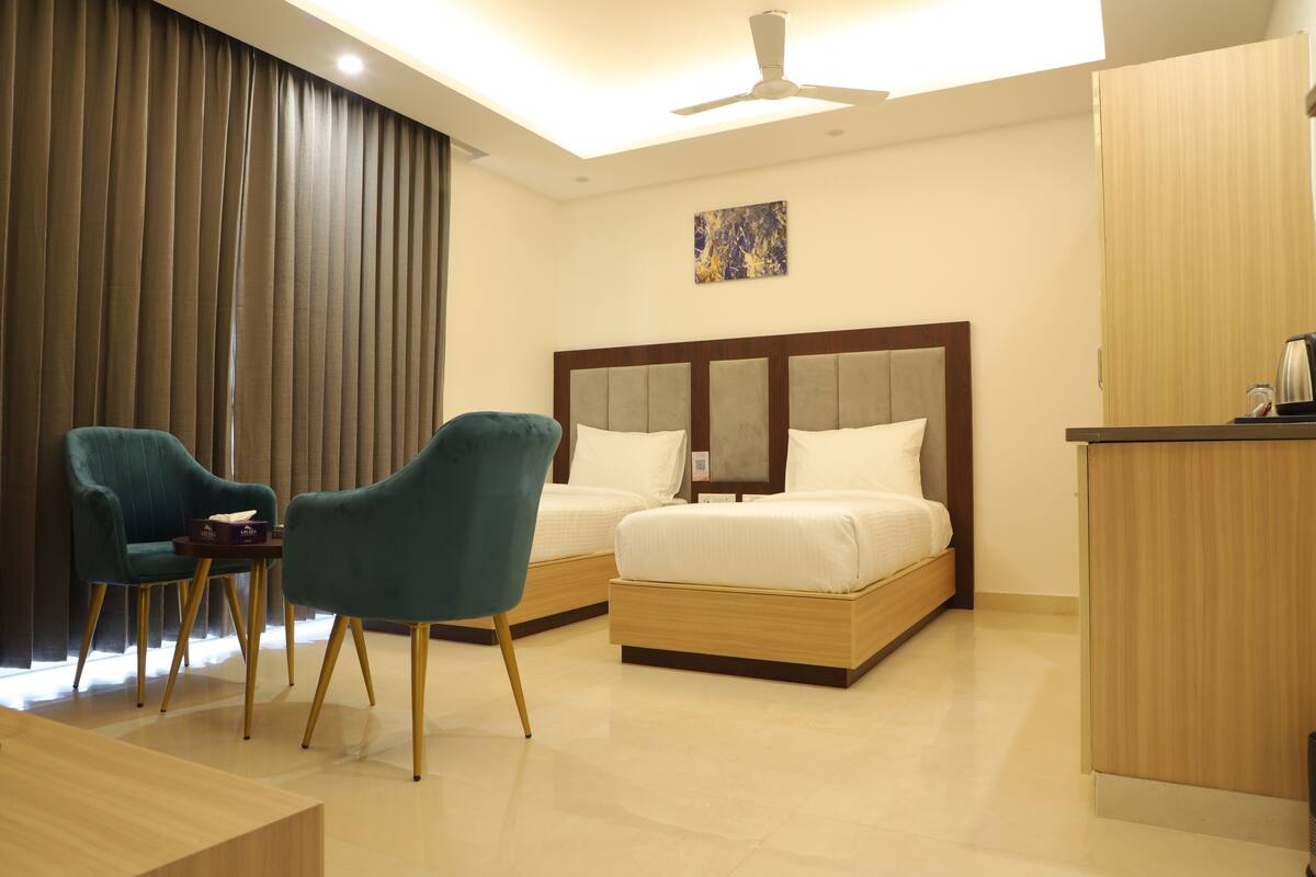 Habitación de hotel con dos camas, un escritorio, una silla y un ventilador de techo.