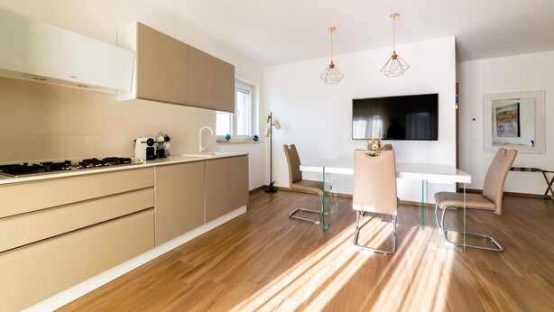 A modern kitchen with a dining area, wooden flooring, and pendant lighting. - Casa ChiaLù by MONHOLIDAY (Monopoli)