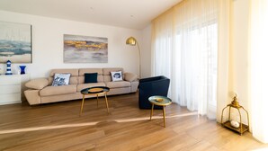 A modern living room with a sofa, two side tables, a floor lamp, and a large window with curtains. - Casa ChiaLù by MONHOLIDAY (Monopoli)