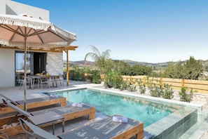 A poolside area with lounge chairs, a table, and an umbrella.