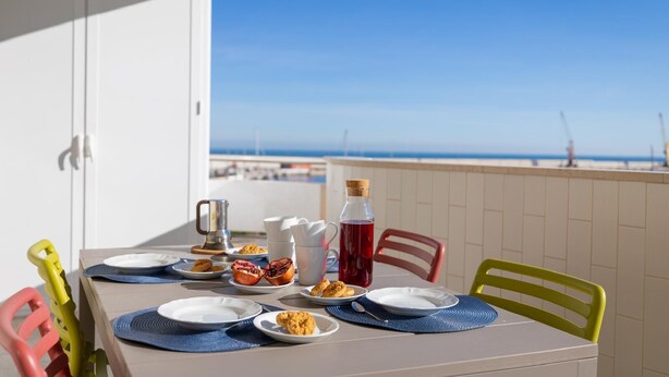 A balcony table with plates, cutlery, and a bottle, overlooking a beach. - La stella sul mare by Monholiday (Monopoli)