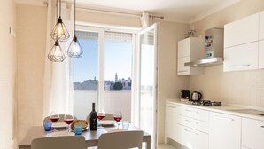 A dining area with a table set for two, a bottle of wine, and glasses. There is a view of the city through the window. - La stella sul mare by Monholiday (Monopoli)