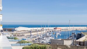 A marina with boats docked, a clear blue sky, and a distant view of the sea. - La stella sul mare by Monholiday (Monopoli)