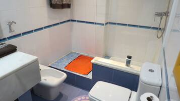 A small bathroom with a toilet, bidet, and shower.