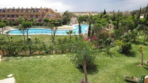 Un hotel con piscina, exuberante vegetación y vistas del entorno.