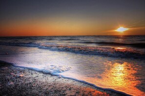 Una playa al atardecer, con olas rompiendo suavemente en la orilla.