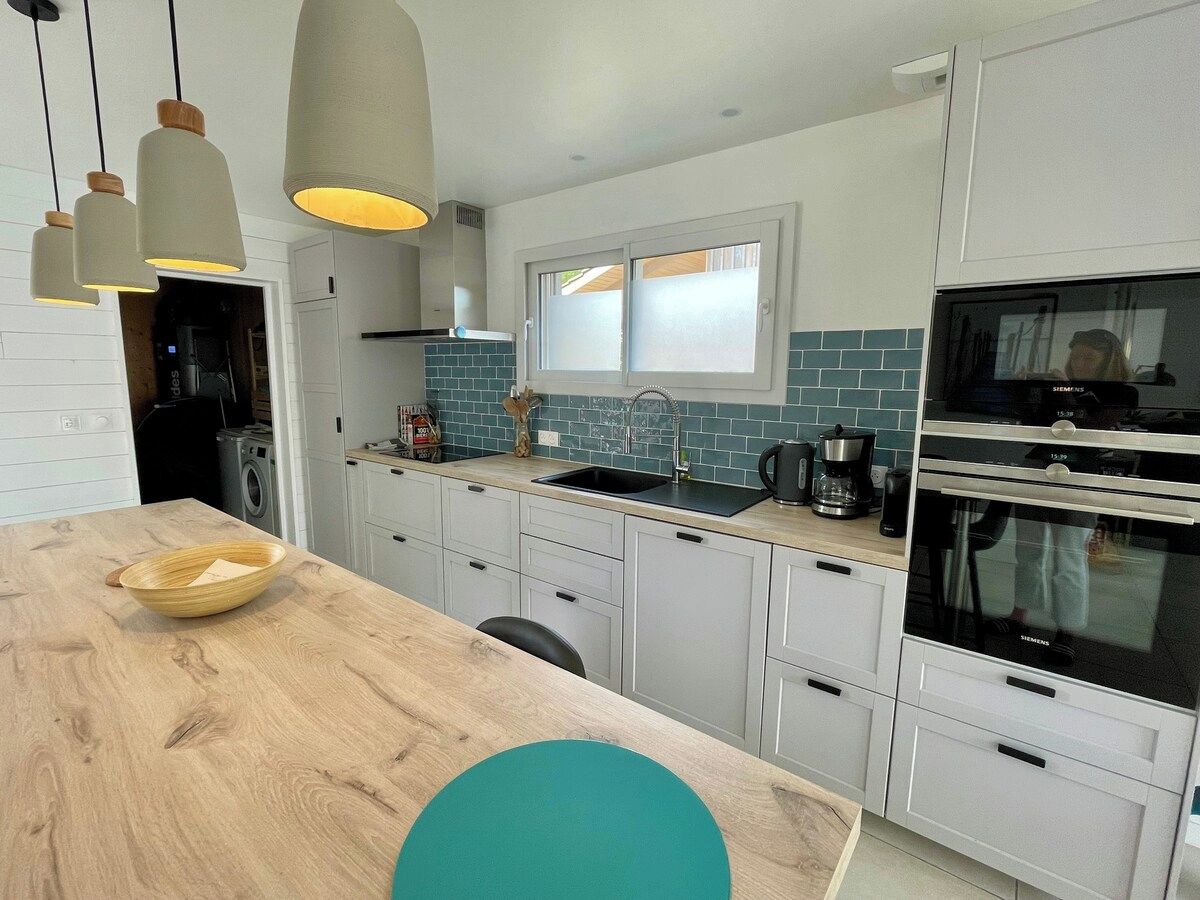 Une cuisine moderne avec des meubles blancs, un plan de travail en bois, un évier et un four Siemens.