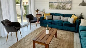 Ein modernes Wohnzimmer mit einem blaugrünen Sofa, einem Holztisch und einem schwarzen Sessel.