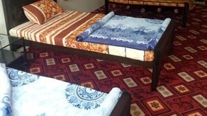 A room with two beds, a mirror, and a patterned carpet. - Balakot International Hotel (Balakot)