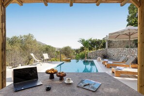 Ein Poolbereich mit Liegestühlen, einem Laptop und Frühstücksangeboten.