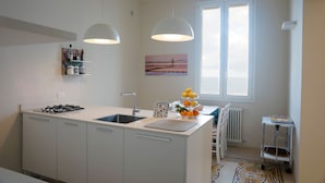 Una cocina moderna con una isla central, armarios blancos, estufa a gas e iluminación colgante.