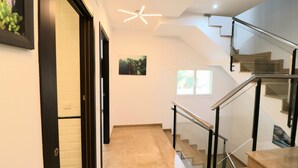 Un interior moderno con una escalera, un cuadro en la pared y una lámpara en el techo.