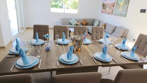Comedor con una larga mesa dispuesta para ocho personas, rodeada de seis sillas.