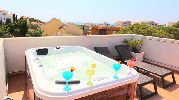 Una terraza en la azotea con bañera de hidromasaje, sillones de descanso y una mesa con bebidas.