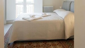 Un dormitorio con cama, ventana y radiador.