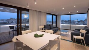 A modern living room with a dining table, sofas, and a view of the cityscape. - Terrammare apartment (Trapani)