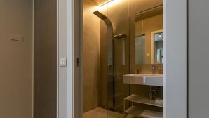 A modern bathroom with a glass shower enclosure, a white sink, and a mirror. - Terrammare apartment (Trapani)
