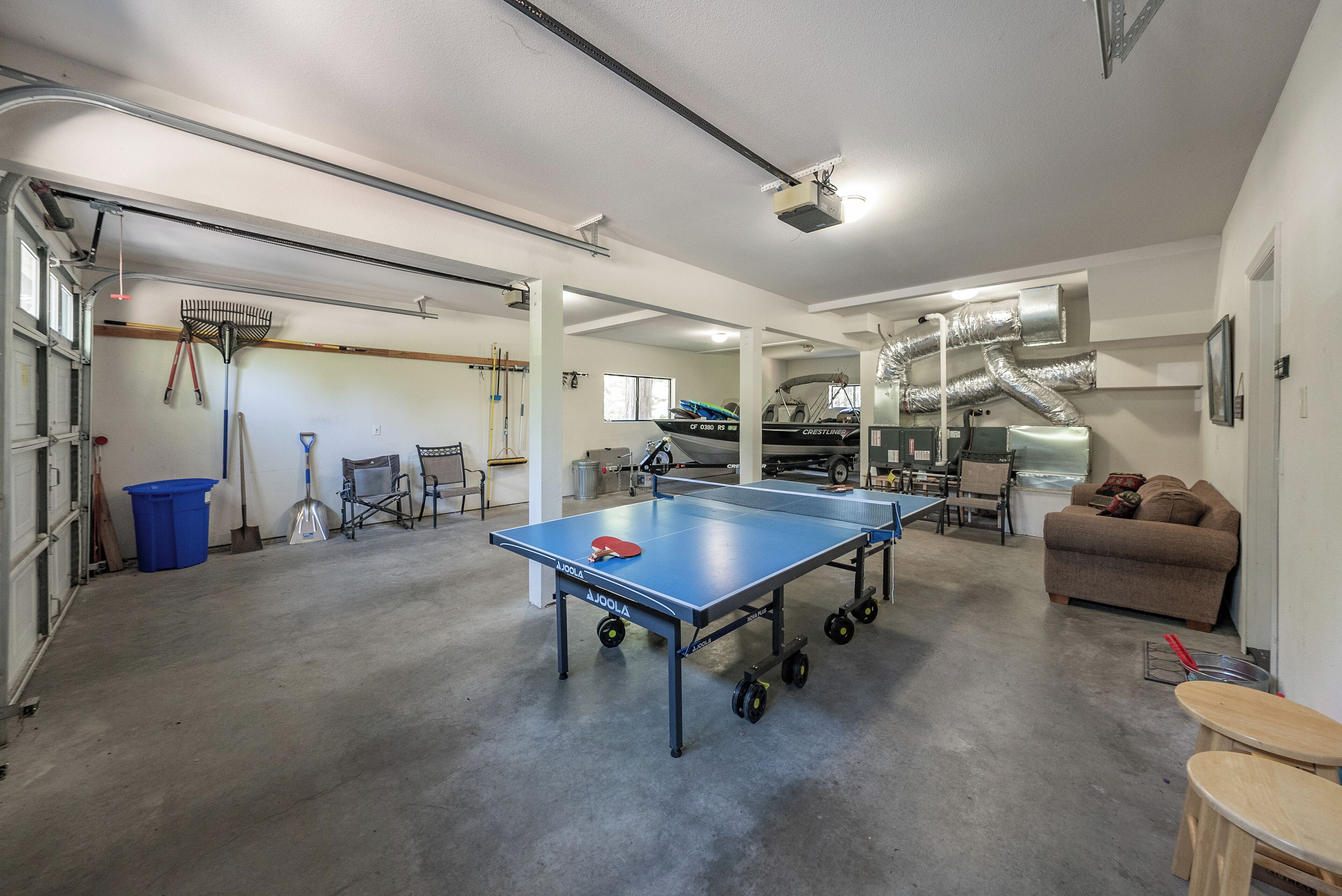 Amplio espacio interior con mesa de ping pong, sofá y diverso equipo deportivo.