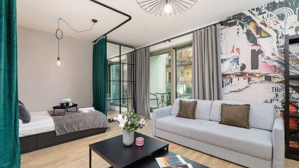 Una sala moderna con un sofá, una mesa de centro y una cama con cortinas.