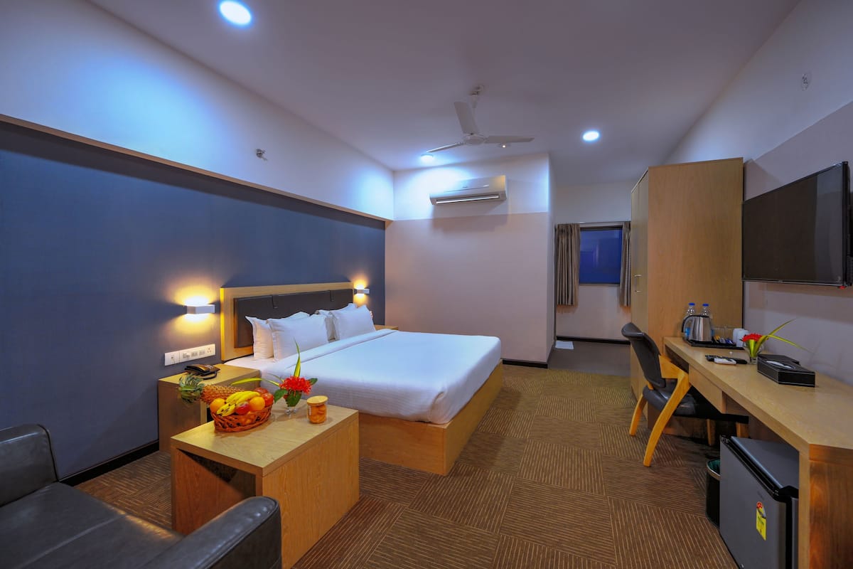 A hotel room with a bed, desk, chair, and a television.