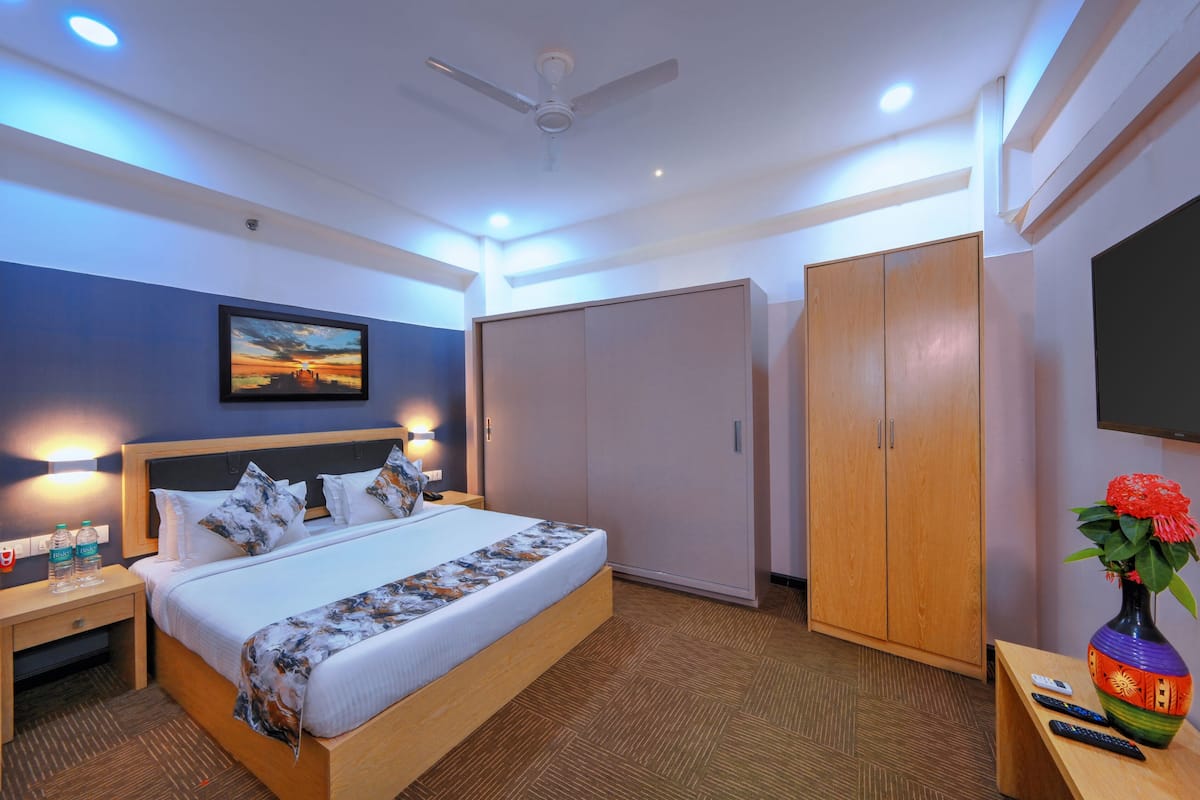 A hotel room with a bed, bedside tables, a wardrobe, a TV, and a decorative vase.