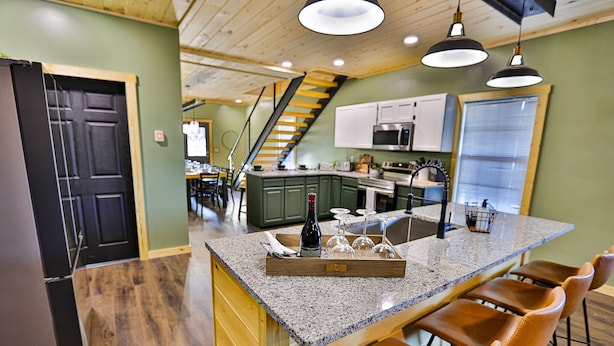 A kitchen with a granite countertop, wooden cabinets, and a built-in island with bar stools. - Best of the Smokies! •Game Room•GSMNP•Theater•Sleep 16•Hot Tub•Flat Parking (Sevierville)