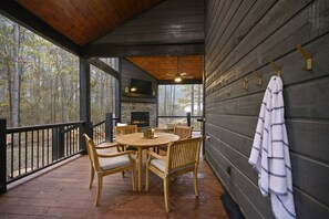 A wooden deck with a round table and chairs, a fireplace, and a hanging towel.
