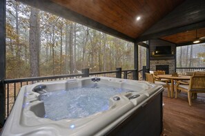 A hot tub on a wooden deck with a view of a forest.