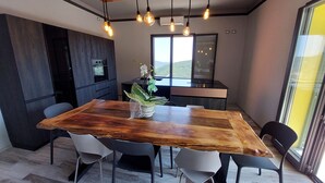 Un comedor moderno con una gran mesa de madera, seis sillas y una lámpara colgante.