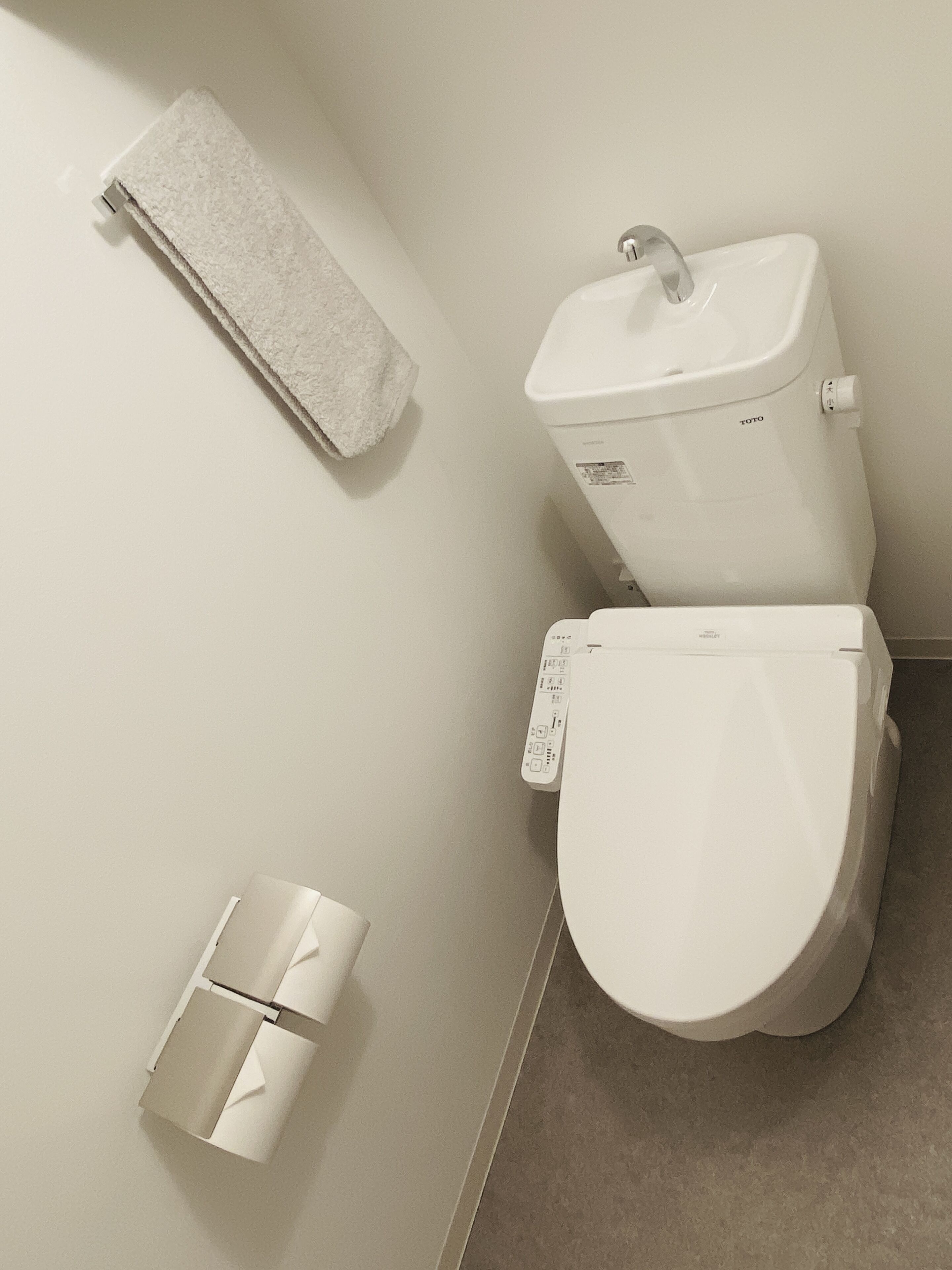 A modern bathroom with a toilet, a towel rack, and a toilet paper holder.